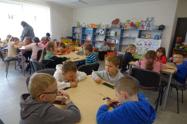 dzieci siedzą przy stlikach i robią zakłądki do książek