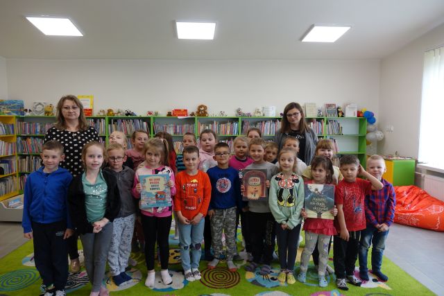 dzieci i 2 kobiety pozują do zdjęcia, w tle regały z książkami