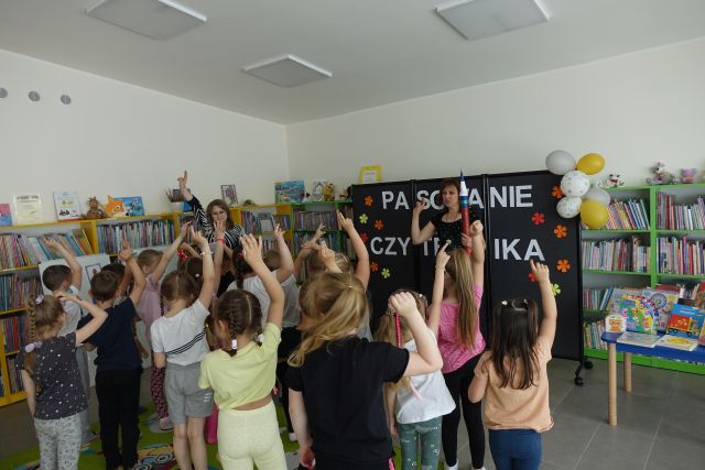 dzieci stoją z podniesionymi prawymi rękoma przed dwoma kobietami