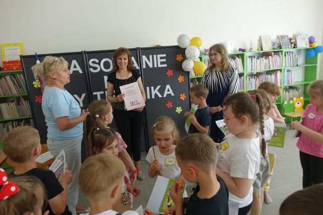 dzieci i nauczycielka wręczają dyrektorce biblioteki podziękowanie