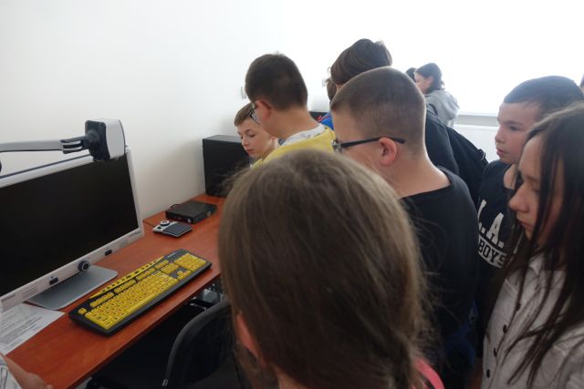 młodzież stoi przed biurkiem z żółtą klawiaturą