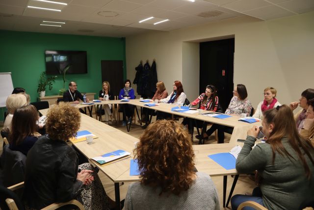 uczestnicy wizyty studyjnej siedzą przy stołach ułożonych w owal