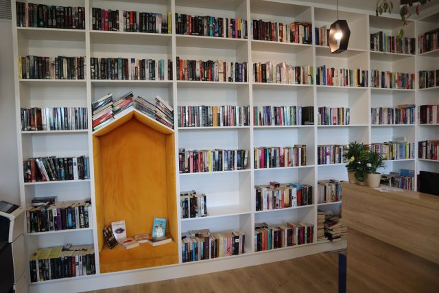 białe regały z książkami, pośrodku żółte siedzisko