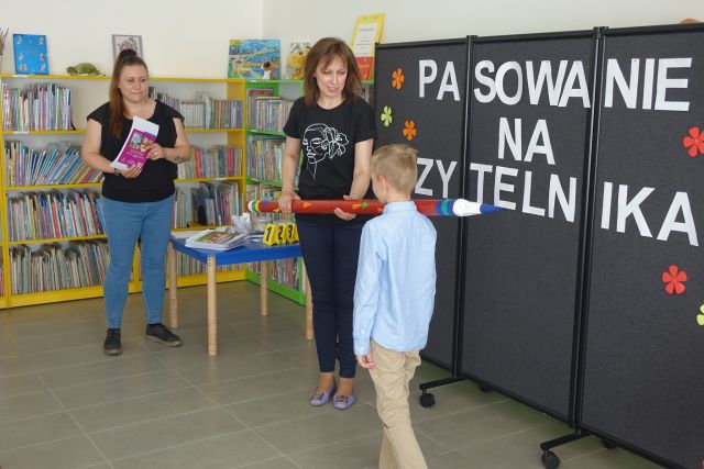 kobieta pasuje ogromnym ołówkiem chłopca