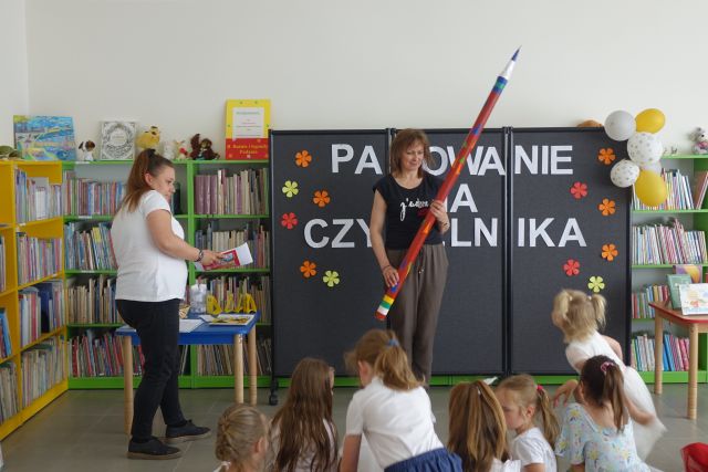 kobieta stojąca trzyma w rękach ogromny ołówek 