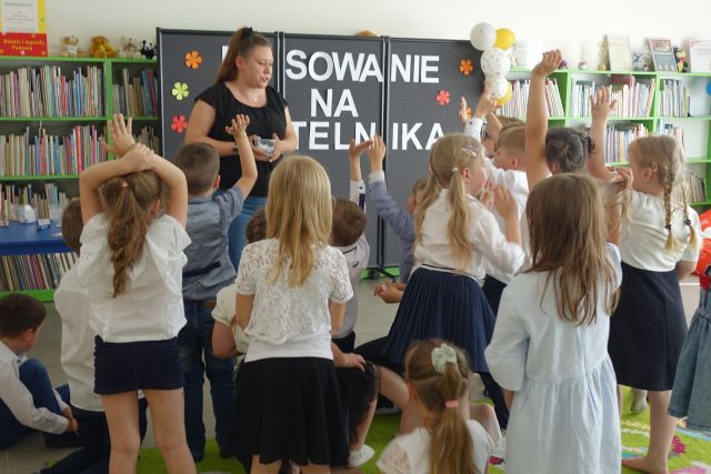 dzieci stoją z podniesionymi dłońmi przed kobietą