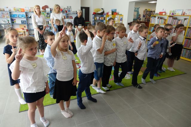dzieci stoją z podniesionymi dwoma palcami i skłądają przysięgę