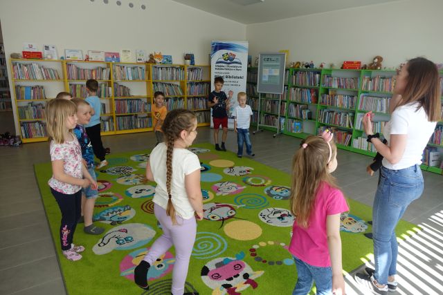 dzieci i kobieta stoją na kolorowym dywanie