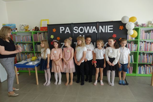 dzieci stoją na tle czarnej tablicy