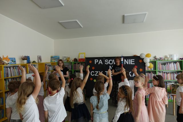 dzieci stoją przed dwoma kobietami i skłądają przysięgę z dwoma palcami u góry