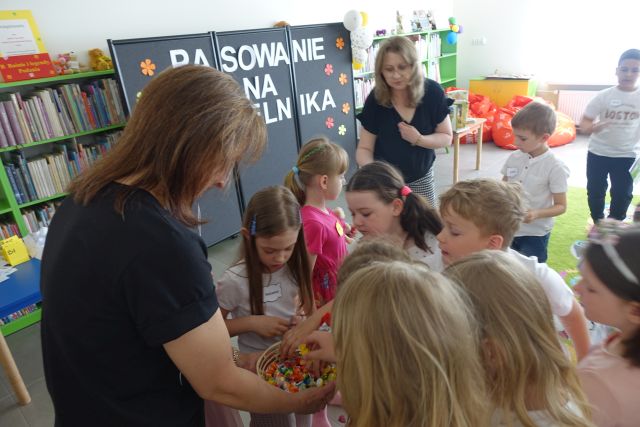 kobieta częstuje przedszkolaki cukierkami