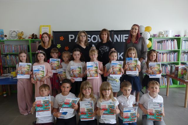 przedszkolaki pozują do zdjęcia grupowego z 2 przedszkolankami i 2 bibliotekarkami