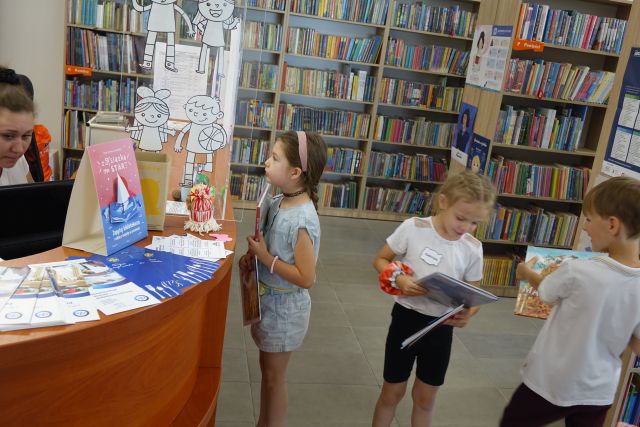 dzieci stoją przed biurkiem, żeby wypożyczyć książki