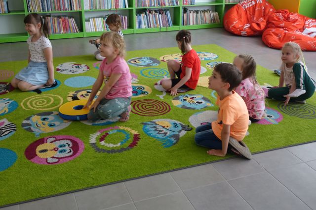 dzieci siedzą na kolorowym dywanie