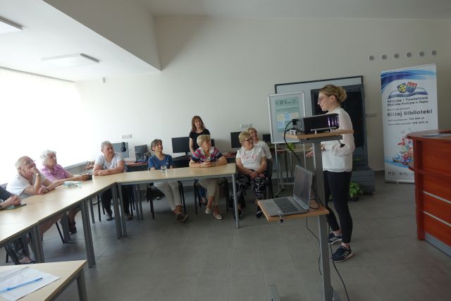 kobieta przemawia do siedzących seniorek