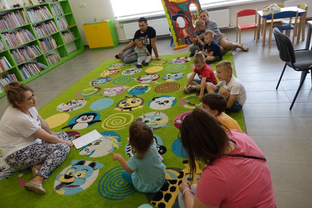 dzieci i rodzice siedzą na kolorowym dywanie