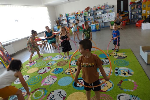 dzieci na kolorowym dywanie kręcą hula hop