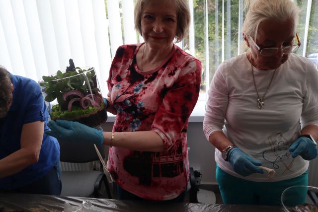 kobieta pokazuje stworzony przez siebie ogród w słoiku