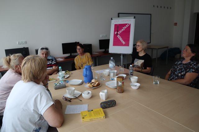 uczestniczki klubu czytelniczego rozmawiają o książkach siedząc przy stołach