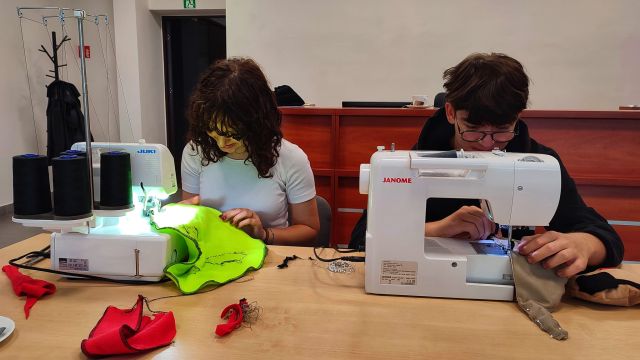dziewczyna i chłoipak szyją na maszynie maskotki