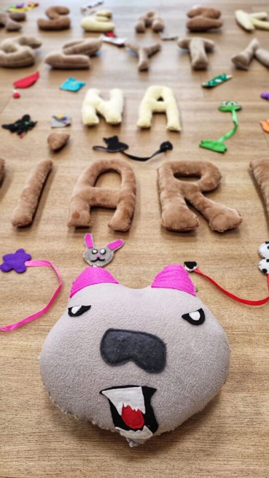 maskotka i litery uszyte z materiałów ułożone na podłodze