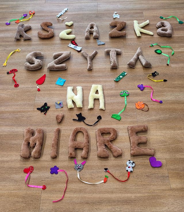 napis książka szyta na miarę uszyty z materiałów ora uszyte zakjładki do książek rozłożone na podłodze