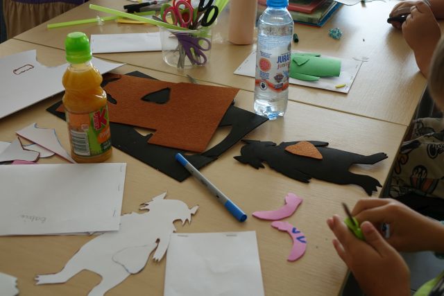 kartki papieru, materiały i stworzone przez dzieci kukiełki