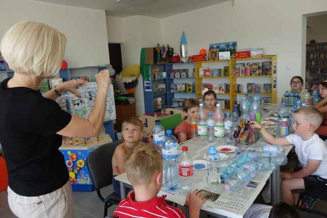 dzieci przy stołach tworzą bukiety z plastikowych butelek