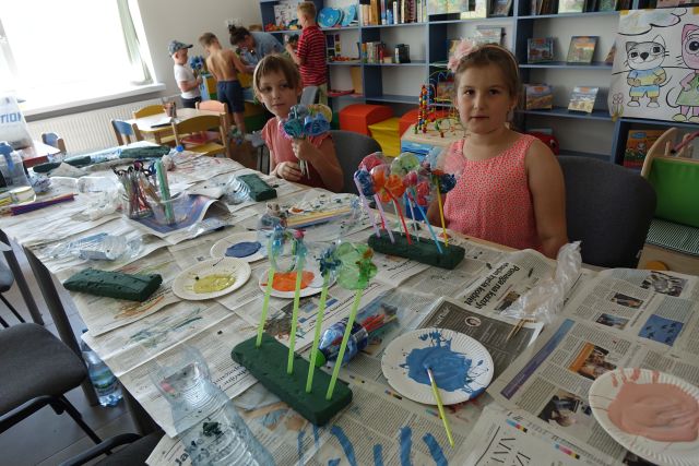 dzieci prezentują wykonane przez siebie bukiety z plastikowych butelek