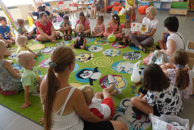 dzieci i rodzice siedzą w okręgu na kolorowym dywanie