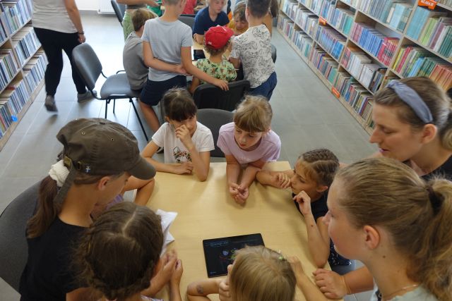 dzieci przy stołąch rozwiązują zagadki