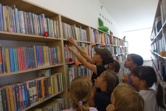 dzieci szukają na regale książkę