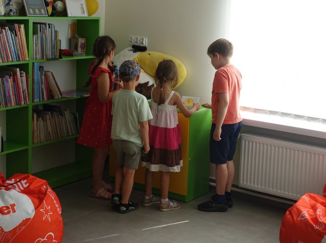 dzieci szukają na kolorowej kmomodzie koperty z zagadką