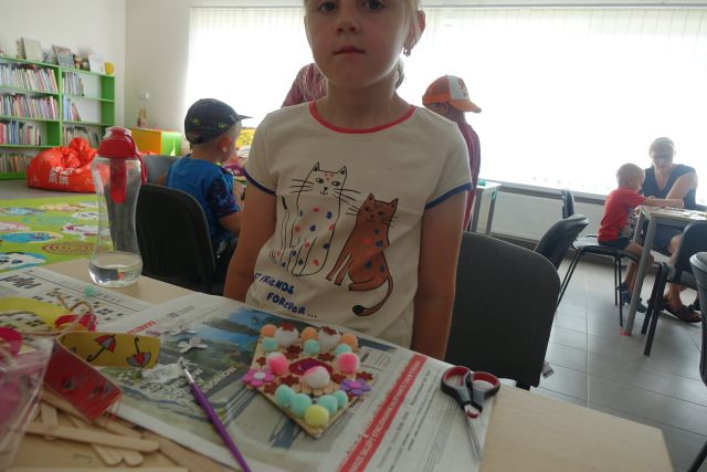 dziewczynka pokazuje wykonany przez siebie domek z patyczków