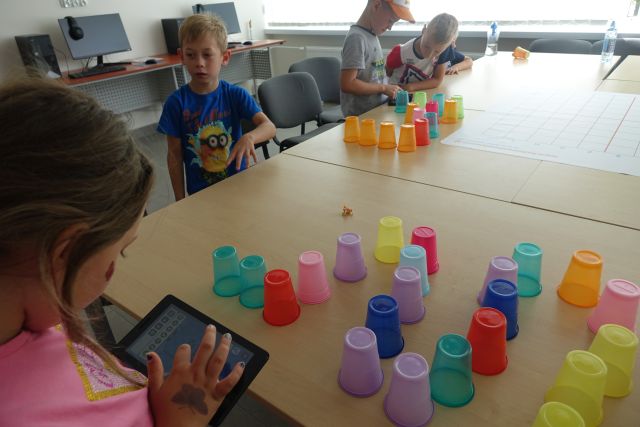 dzieci kodują przy pomocy kolorowych kubeczków