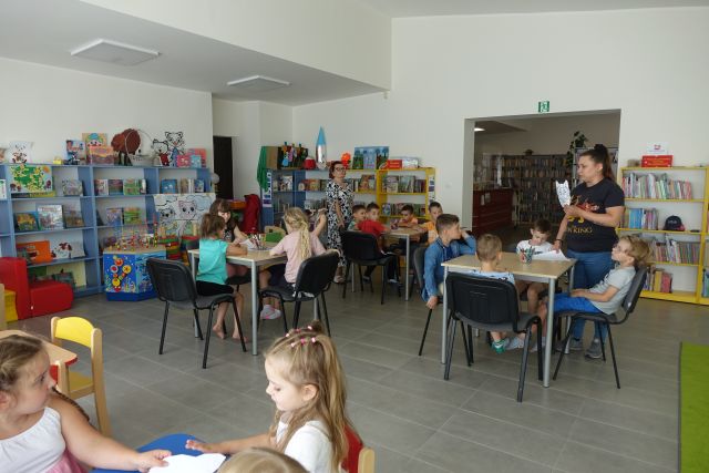 dzieci siedzą przy stolikach i malują