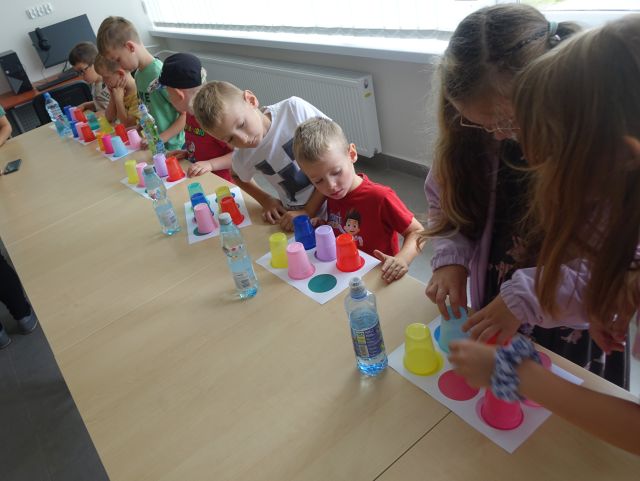 uczestnicy zajęć programują układając według kodu kolorowe kubeczki