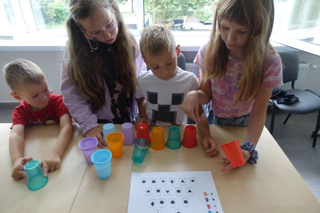 uczestnicy zajęć programują układając według kodu kolorowe kubeczki