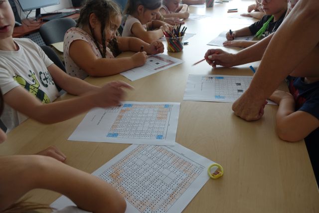 przedszkolaki rozwiązują zadanie na kartkach