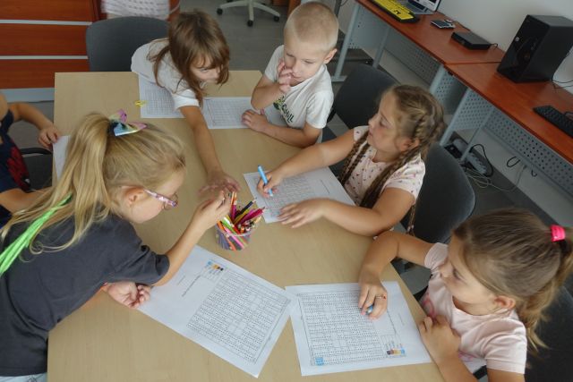 przedszkolaki rozwiązują zadanie na kartkach