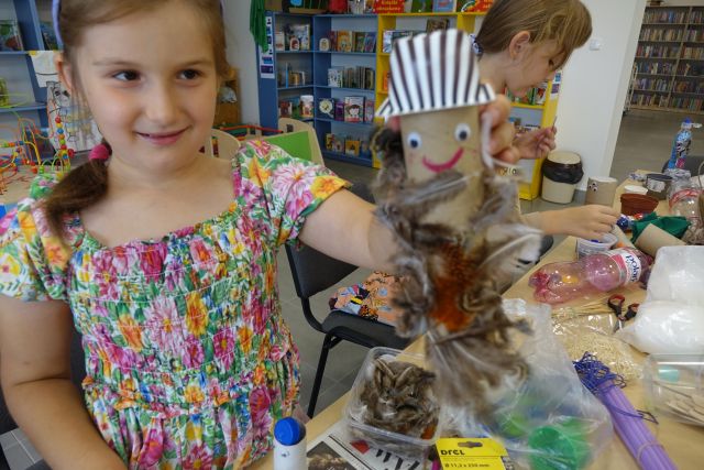 dziewczynka pokazuje wykonaną przez siebie zabawkę z materiałów recyklingowych