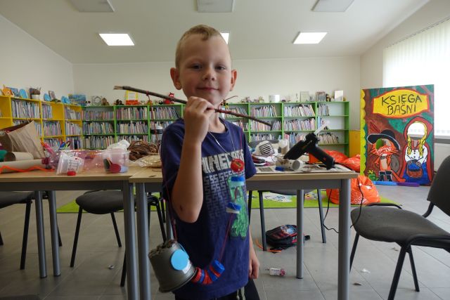 chłopiec pokazuje wykonaną przez siebie zabawkę z materiałó recyklingowych