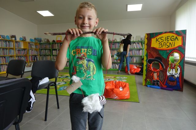 chłopiec pokazuje wykonaną przez siebie zabawkę z materiałó recyklingowych