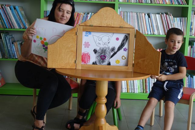 dzieci pokazują ilustracje w teatrzyku kamishibai