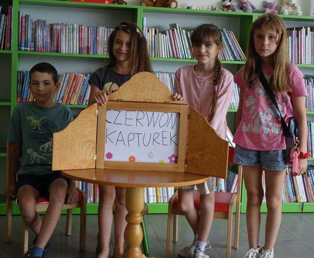 dzieci pokazują ilustracje w teatrzyku kamishibai