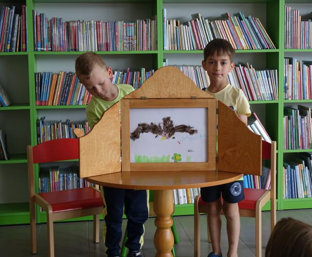 dzieci pokazują ilustracje w teatrzyku kamishibai