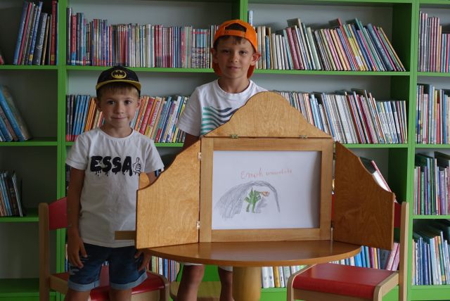 dzieci pokazują ilustracje w teatrzyku kamishibai