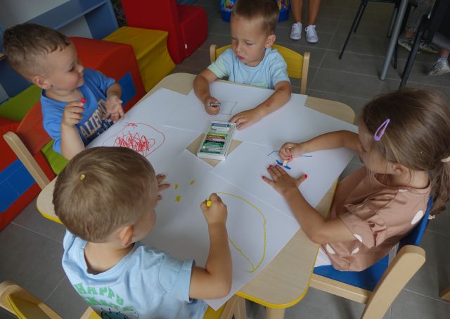 4 przedszkolaków rysujących na kartkach