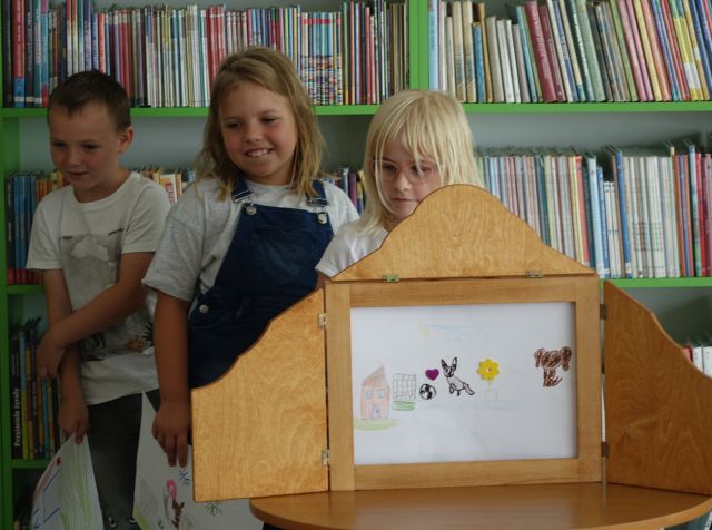 2 dziewczynki i chłopiec pokazujące swoją ilustrację w teatrzyku kamishibai