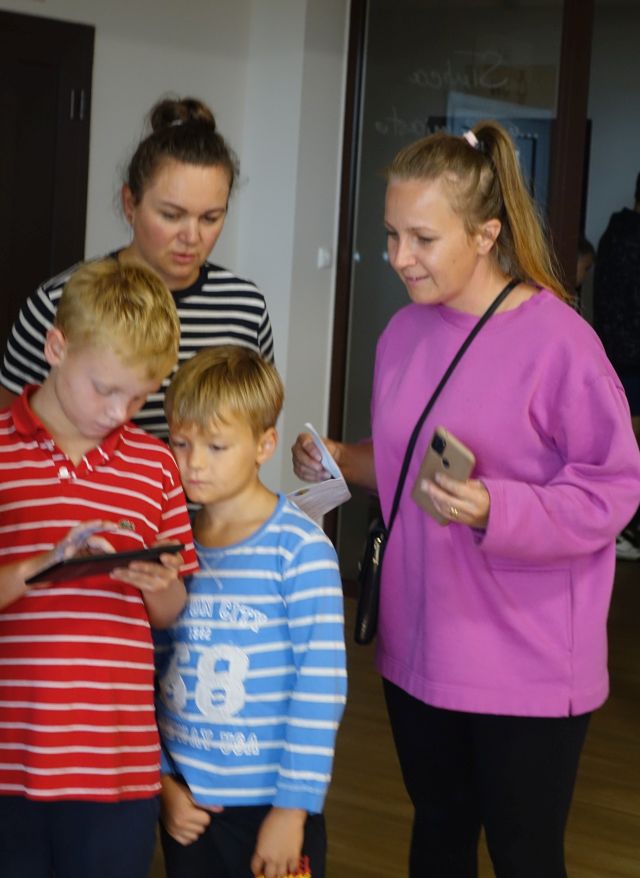 2 kobiety i 2 dzieci rozwiązują zadanie przy użyciu tabletu